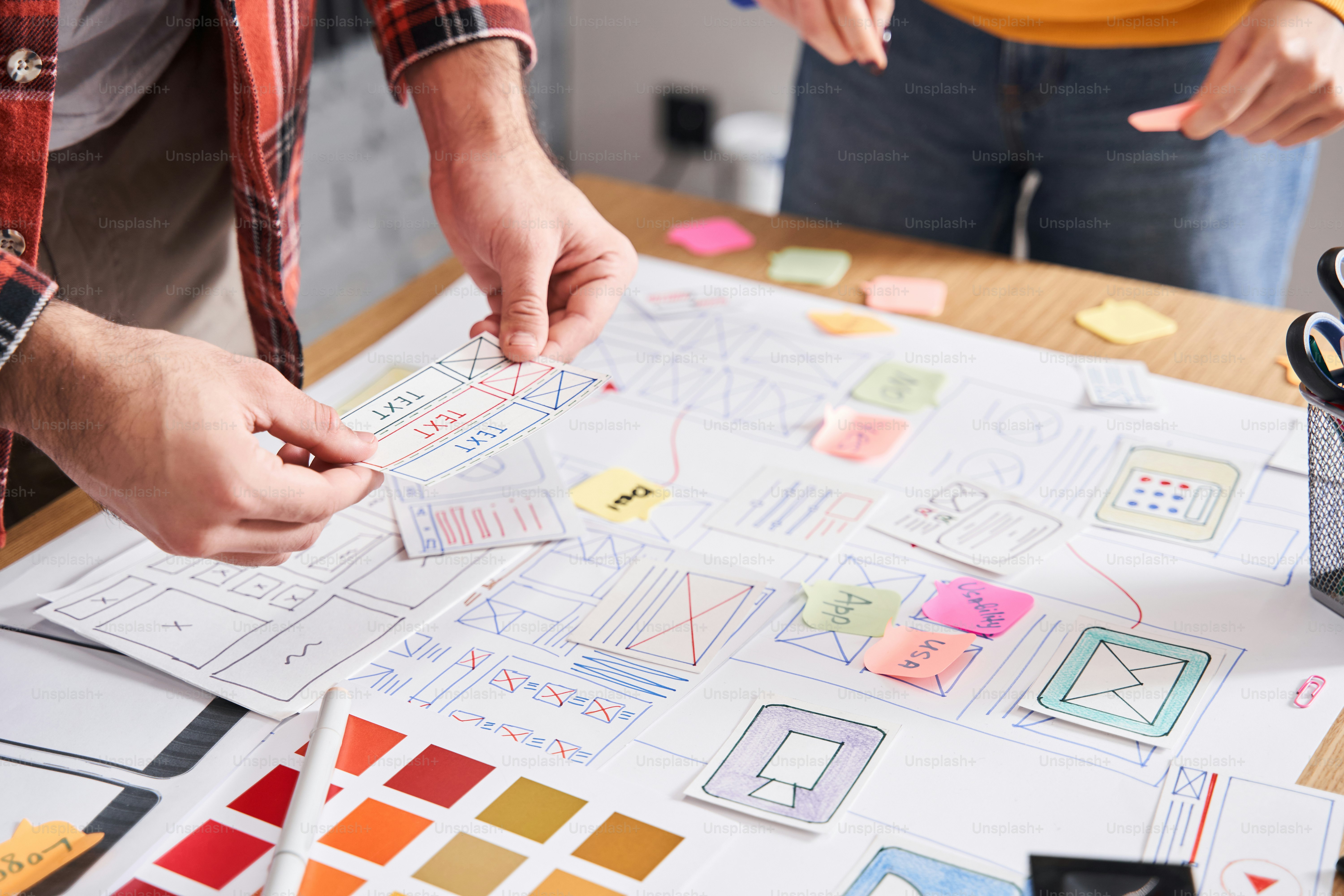 UI/ux constructors. People working as a mobile app designers while making layout at the office table. Development of the user interface of the program. Intuitive interface of the program concept